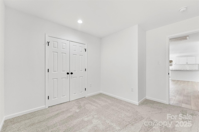 unfurnished bedroom with carpet floors, baseboards, and a closet