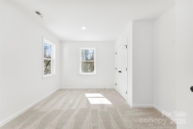 unfurnished bedroom featuring baseboards, visible vents, and light colored carpet