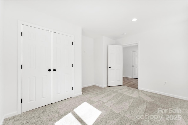 unfurnished bedroom with carpet floors, a closet, recessed lighting, and baseboards