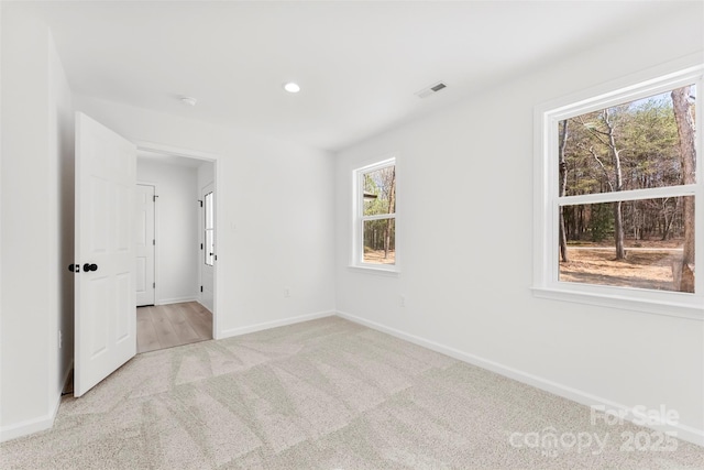 empty room with light carpet, visible vents, and baseboards