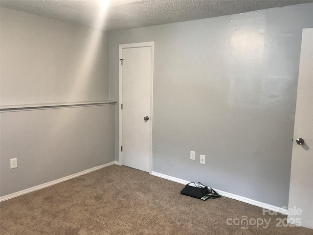 empty room featuring carpet flooring, a textured ceiling, and baseboards