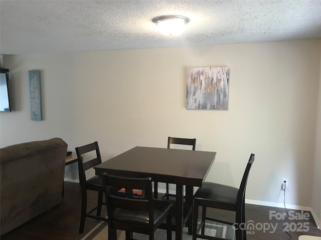 dining space featuring a textured ceiling, wood finished floors, and baseboards