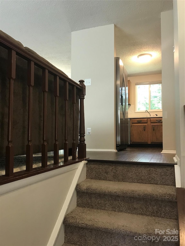 staircase featuring baseboards and a textured ceiling