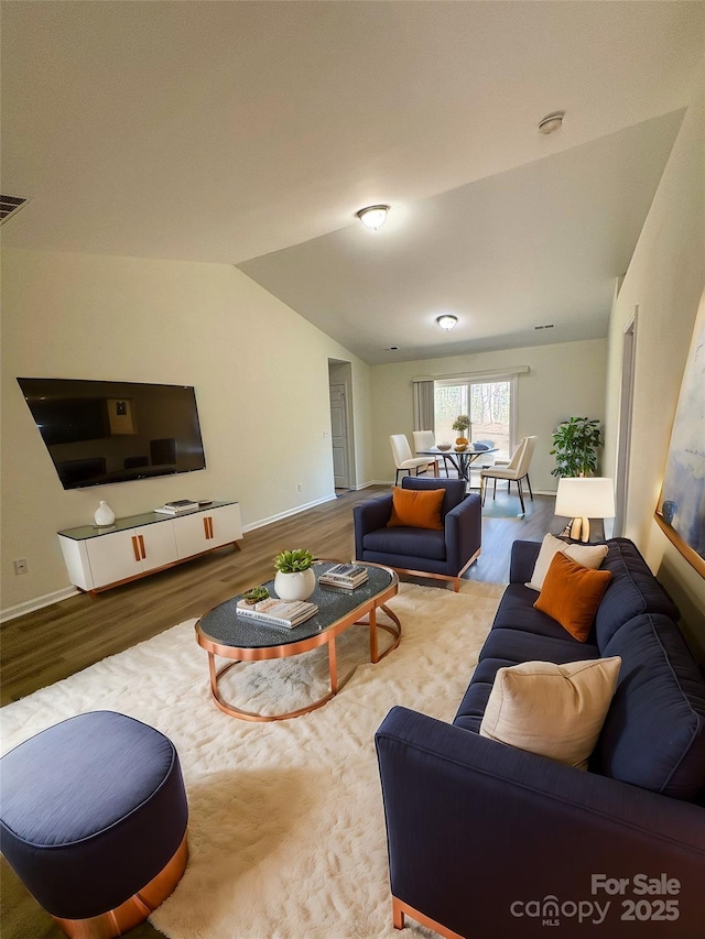 living room featuring baseboards, vaulted ceiling, and wood finished floors