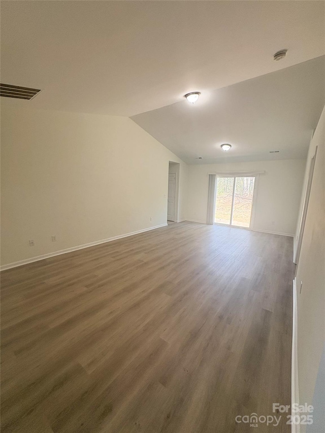spare room with baseboards, visible vents, wood finished floors, and lofted ceiling