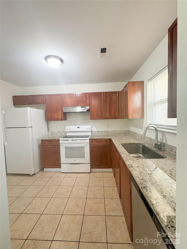 kitchen with white appliances, under cabinet range hood, a sink, light stone counters, and light tile patterned floors