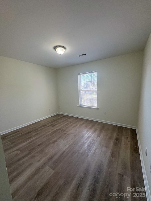 unfurnished room with dark wood finished floors, baseboards, and visible vents