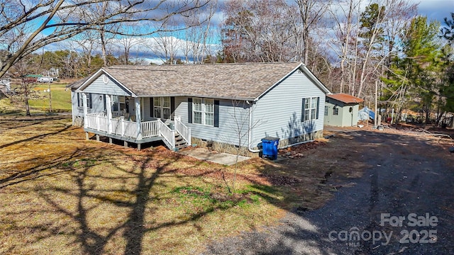 view of front facade featuring roof with shingles, covered porch, a front yard, crawl space, and driveway