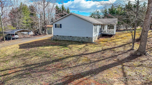 view of side of home featuring a detached carport, crawl space, and a yard