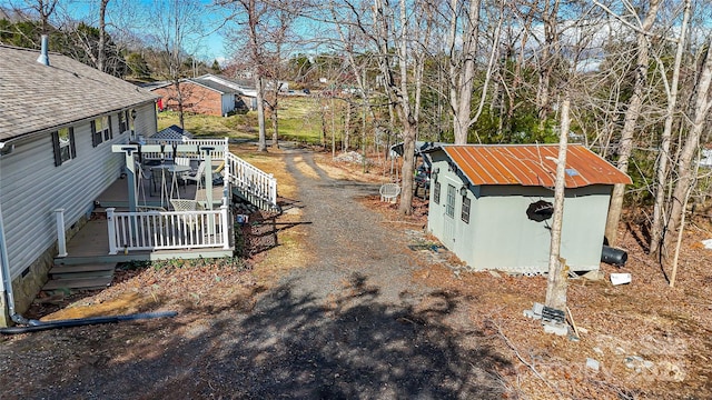 view of yard with an outbuilding, dirt driveway, a wooden deck, and a shed