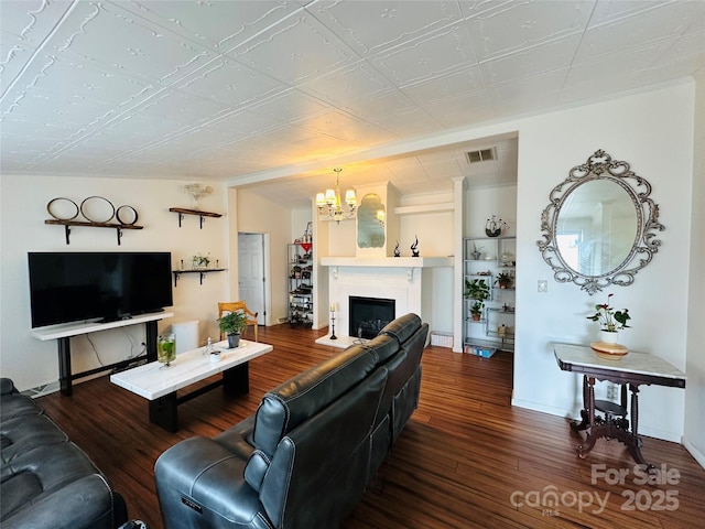 living area featuring a fireplace, visible vents, wood finished floors, a chandelier, and baseboards