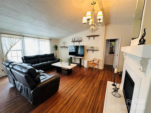 living room featuring lofted ceiling, a notable chandelier, wood finished floors, a fireplace with flush hearth, and an ornate ceiling