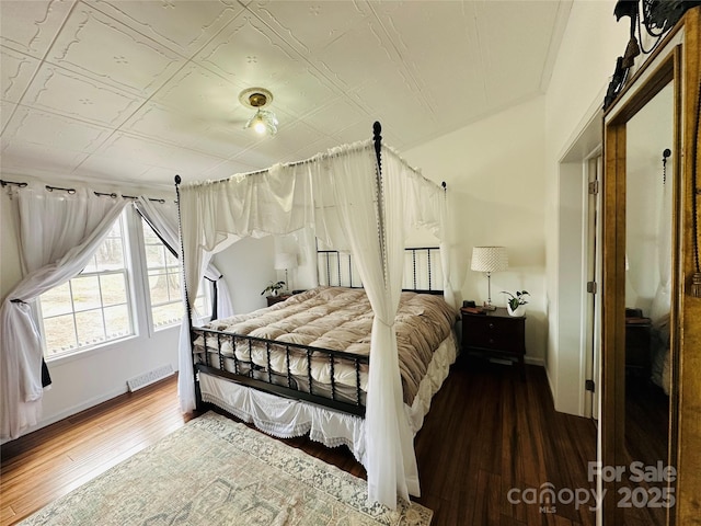 bedroom featuring an ornate ceiling, wood finished floors, visible vents, and baseboards