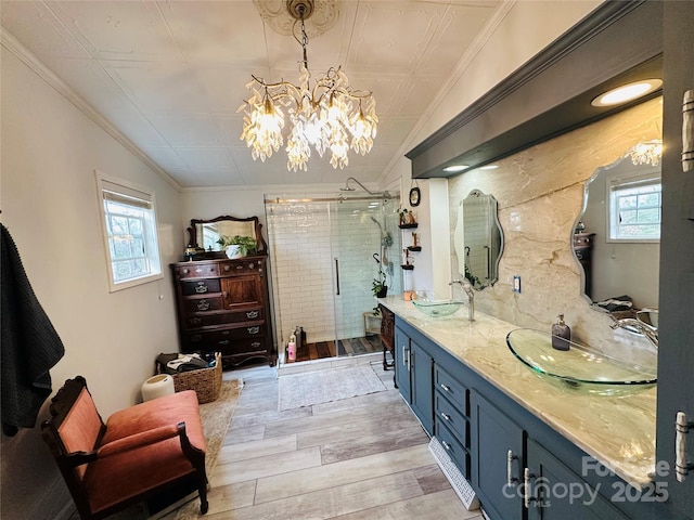 full bathroom featuring double vanity, a stall shower, wood tiled floor, and a sink