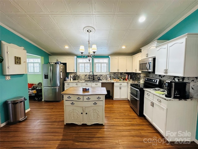 kitchen with a notable chandelier, a sink, white cabinets, appliances with stainless steel finishes, and dark wood-style floors