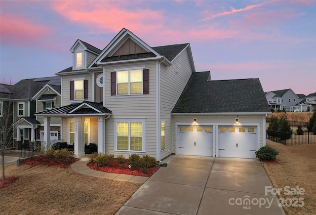 traditional home with driveway, fence, board and batten siding, a shingled roof, and a garage