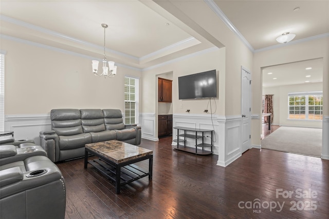 living area with a wainscoted wall, a notable chandelier, dark wood finished floors, crown molding, and a decorative wall