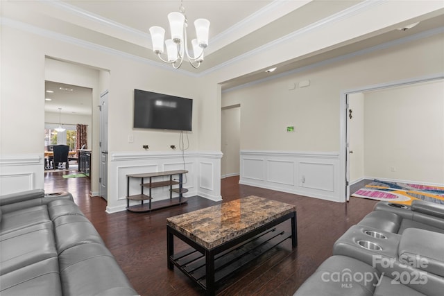 living room with wood finished floors, ornamental molding, wainscoting, a decorative wall, and a notable chandelier