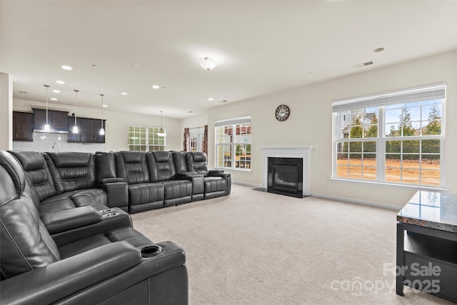 living area featuring visible vents, baseboards, a fireplace with flush hearth, light carpet, and recessed lighting