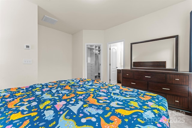 bedroom featuring a spacious closet, visible vents, light colored carpet, and a closet