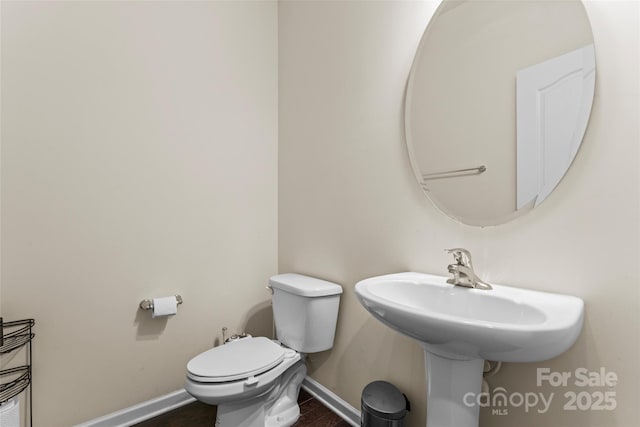 half bath with baseboards and toilet