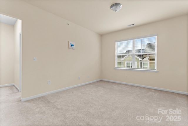 empty room with visible vents, light carpet, and baseboards