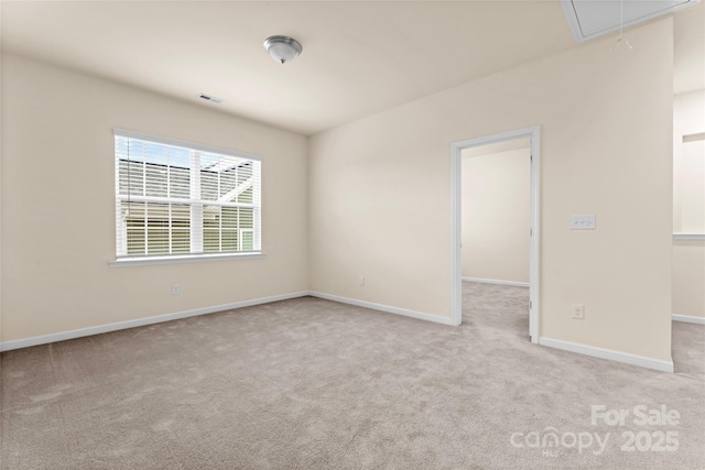 carpeted empty room featuring attic access, visible vents, and baseboards