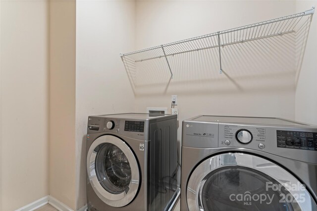 laundry room with laundry area, washing machine and dryer, and baseboards