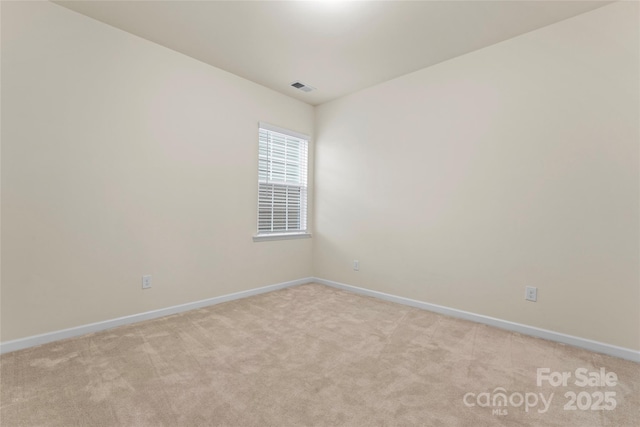 empty room featuring visible vents, light colored carpet, and baseboards