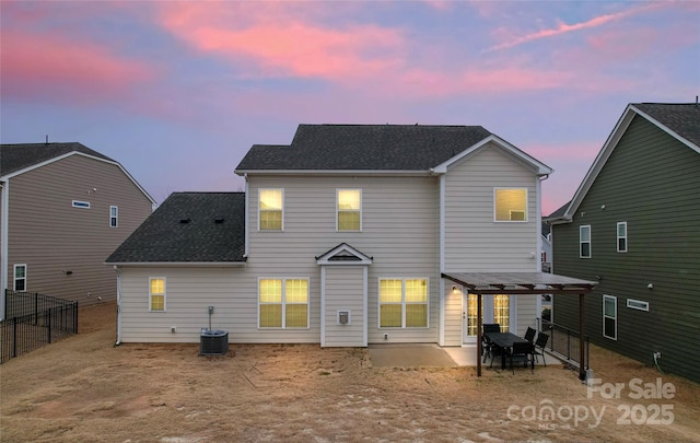 back of house at dusk with a patio, central air condition unit, fence, and a shingled roof