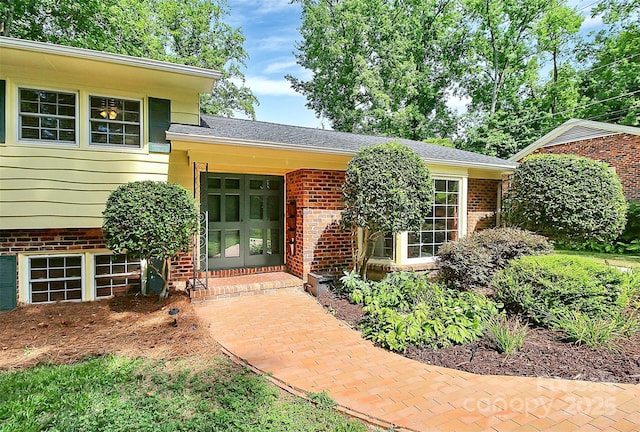 entrance to property with a shingled roof and brick siding