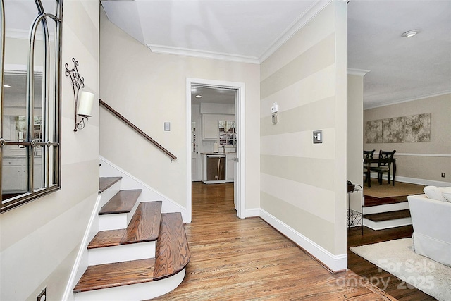 interior space featuring light wood-type flooring, stairway, baseboards, and ornamental molding