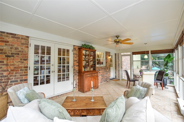 tiled living area featuring brick wall, a ceiling fan, and french doors