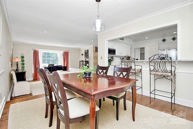 dining space with baseboards, recessed lighting, light wood-type flooring, and crown molding