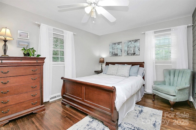 bedroom featuring dark wood-style floors, ceiling fan, visible vents, and baseboards