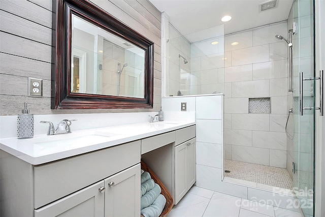 bathroom featuring double vanity, a stall shower, a sink, and visible vents