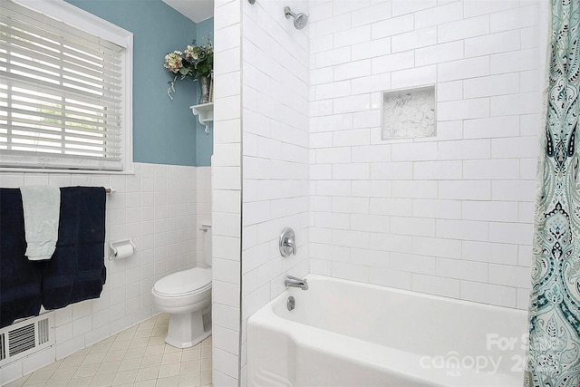 bathroom featuring tile walls, visible vents, toilet, shower / bath combo, and tile patterned floors