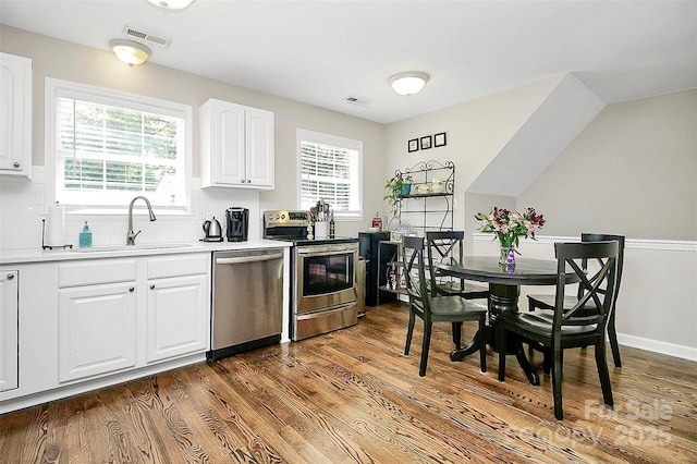 kitchen with visible vents, decorative backsplash, appliances with stainless steel finishes, wood finished floors, and a sink