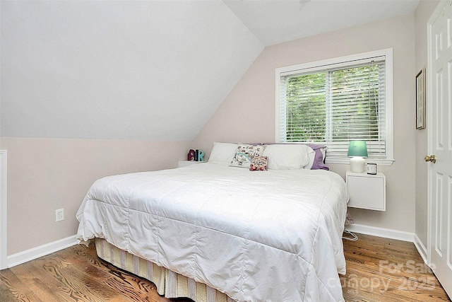 bedroom with baseboards, vaulted ceiling, and wood finished floors