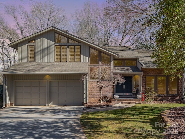 mid-century modern home with a garage, driveway, brick siding, and roof with shingles