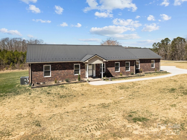 ranch-style house featuring a front yard, brick siding, metal roof, and central AC