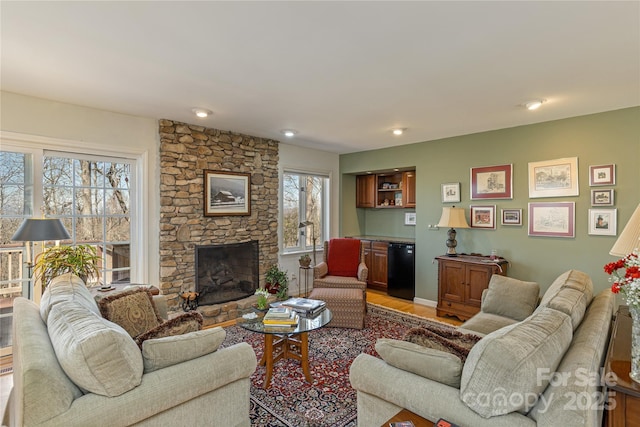 living area with light wood-style floors and a stone fireplace