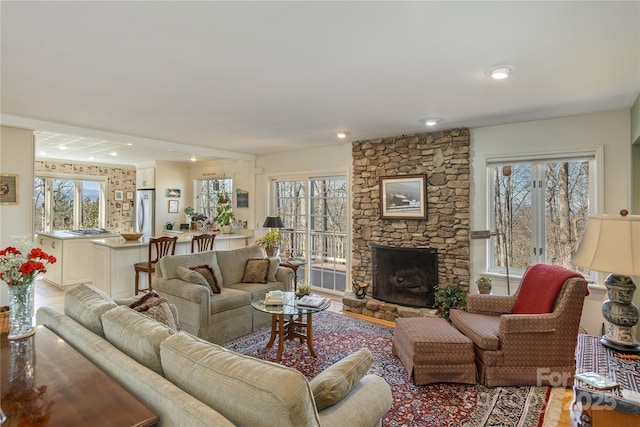 living room featuring a healthy amount of sunlight, recessed lighting, and a stone fireplace