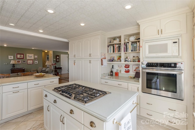 kitchen with an ornate ceiling, stainless steel appliances, light countertops, open floor plan, and a kitchen island