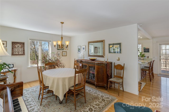 dining area with light wood-style floors, baseboards, and an inviting chandelier