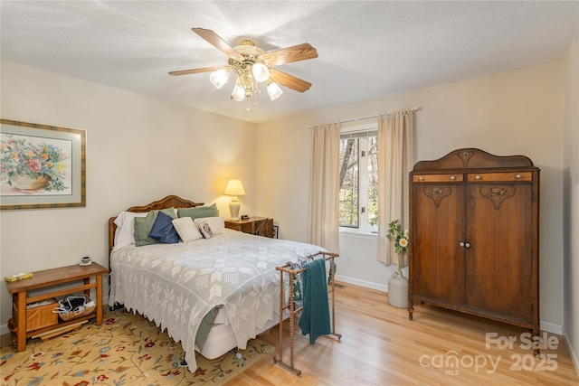 bedroom with a textured ceiling, a ceiling fan, light wood-style flooring, and baseboards