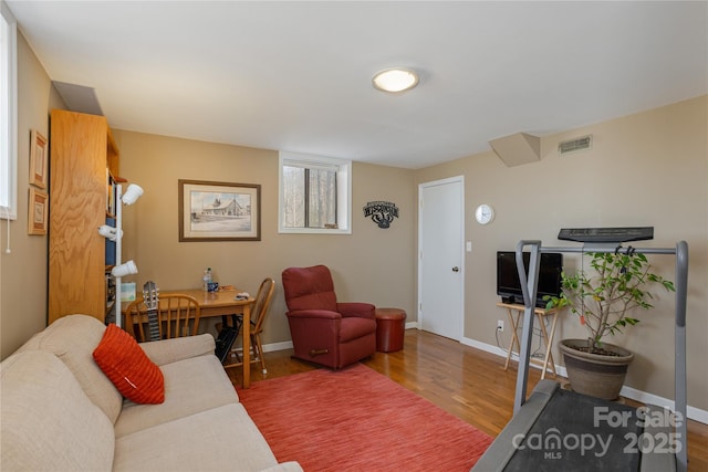 living area featuring wood finished floors, visible vents, and baseboards