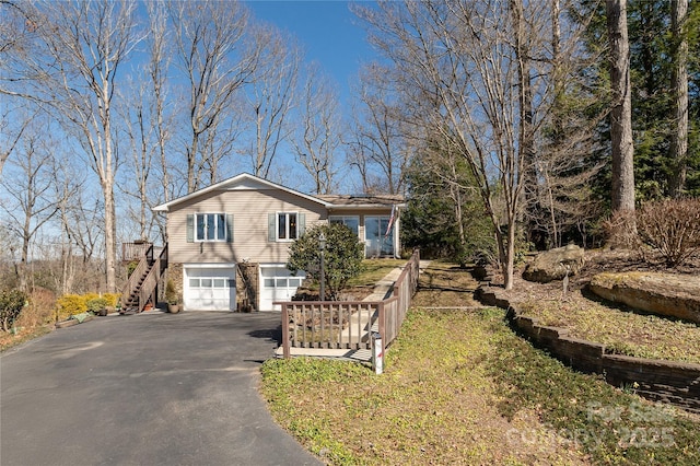 view of front of house featuring a garage, aphalt driveway, and stairway