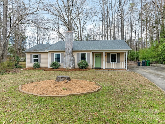 ranch-style home with roof with shingles, a porch, a front lawn, and a chimney