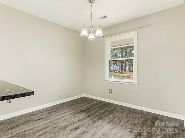 unfurnished dining area with dark wood-type flooring, an inviting chandelier, visible vents, and baseboards